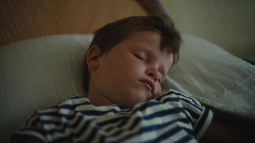 Young boy wearing a striped shirt sleeping in bed
