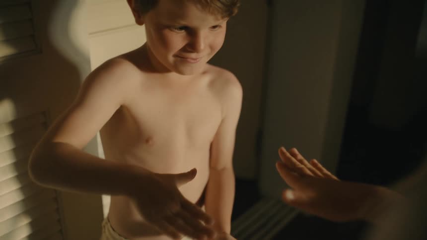 A happy and laughing child playing rockpaperscissors with someone