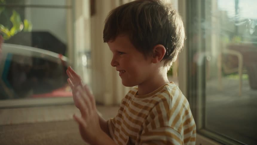 A pair of children play a clapping game while sitting together on the floor during the day