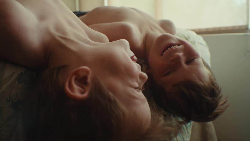 Two children laugh in bed