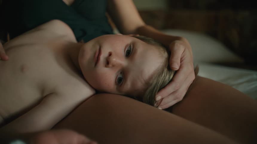 A mother caressing her son lying in bed