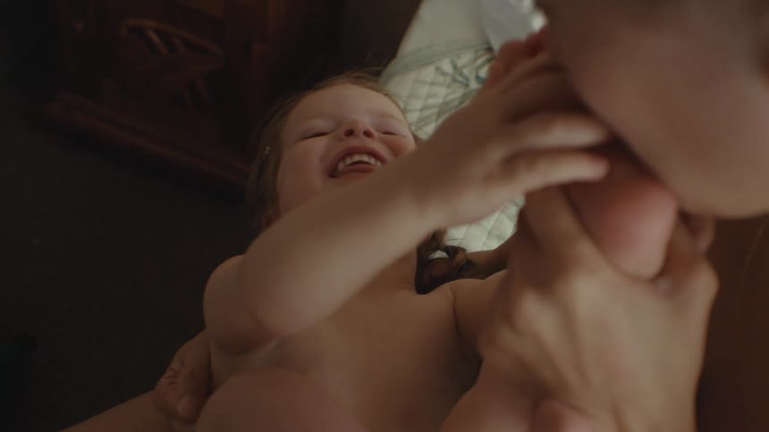 Mother teases child by kissing their feet