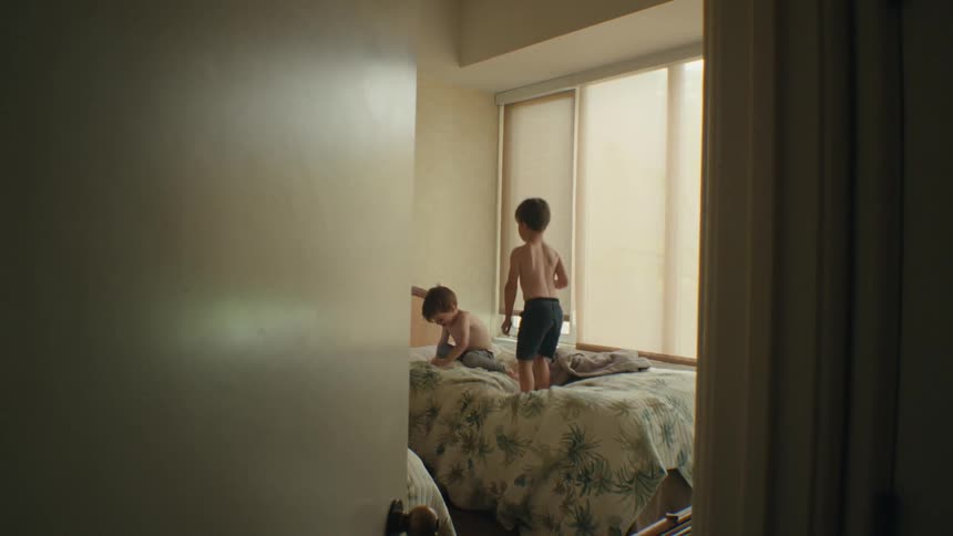 Two kids happily jumping on a bed and having fun
