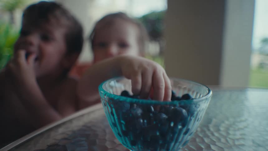 Two children are eating blueberries