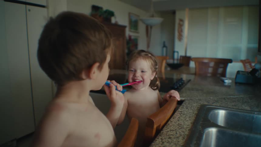 Siblings brushing their teeth on a wooden chair