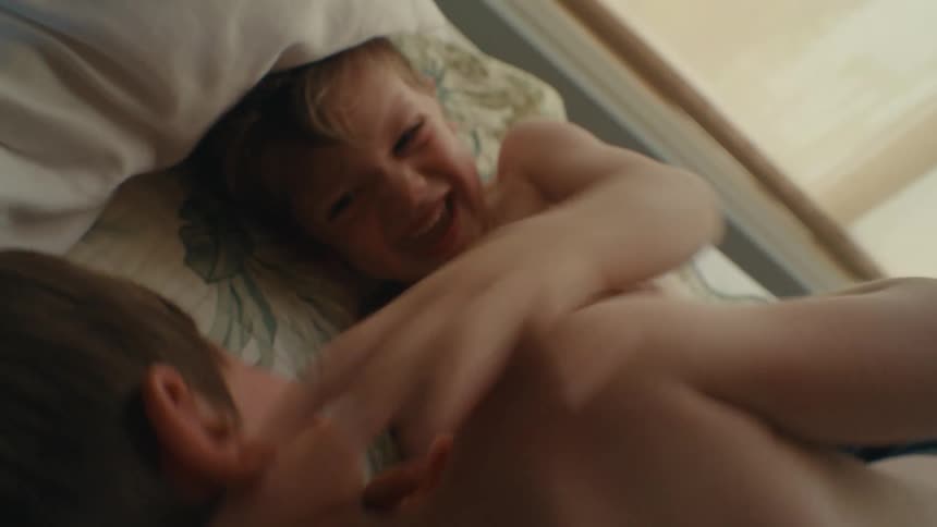 Two young boys on a bed playing wrestling and laughing