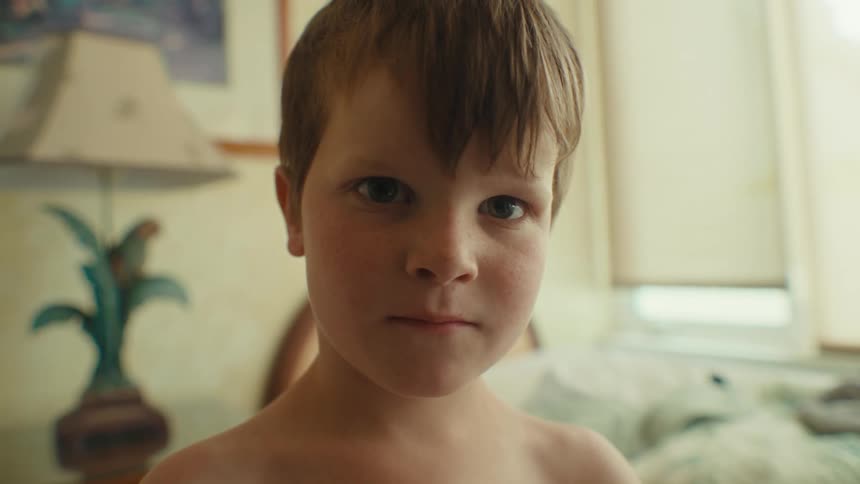 Young boy standing in a bedroom with varied facial expressions