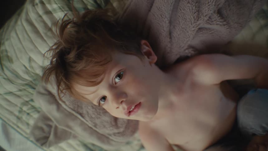 A portrait of a kid laying down on a bed