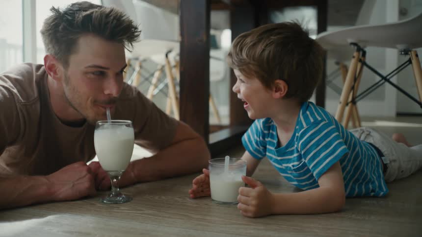 Father and Son Share a Moment of Delight Blowing Bubbles in Milk at Home