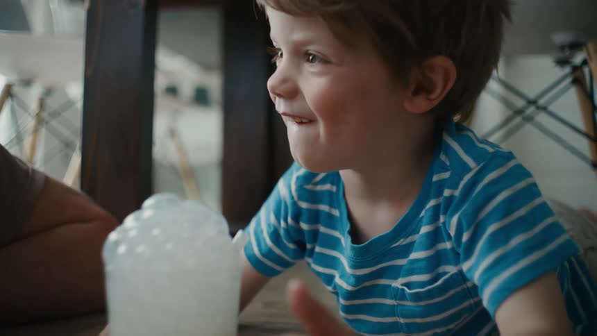 Toddler Grins Up at His Father While Drinking Milk at Home