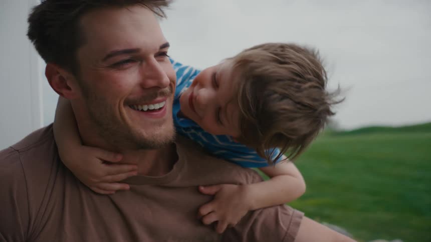Young boy sharing a quiet, present moment on his father’s back outdoors