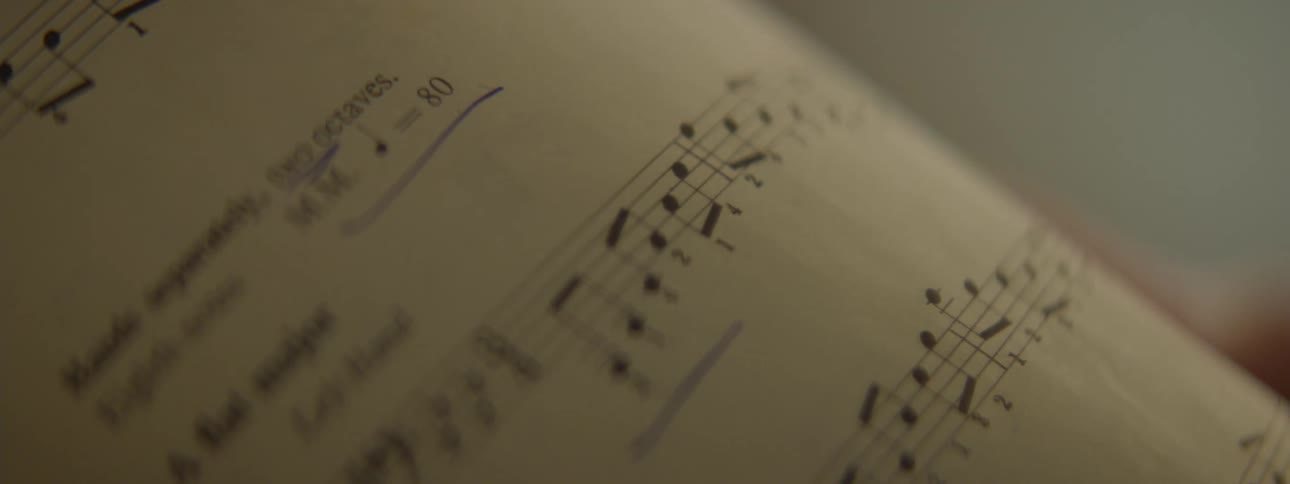 An extreme close up of a music book with notes for songs on each page