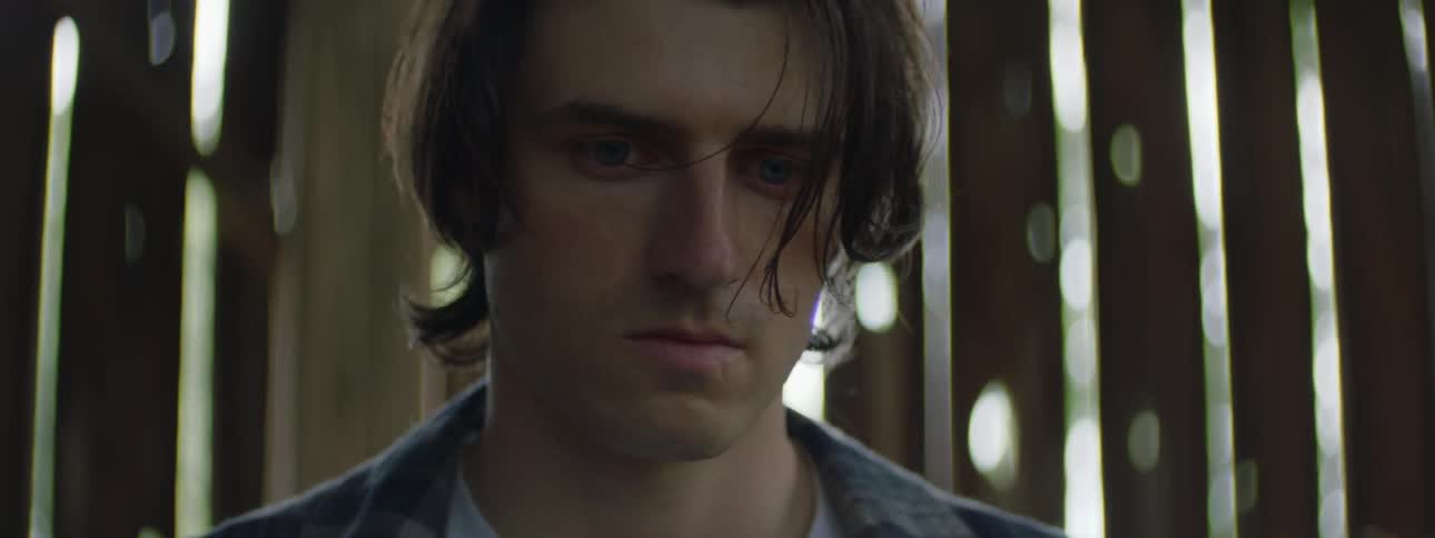 Worker man in a barn putting away his working gloves with a somber look