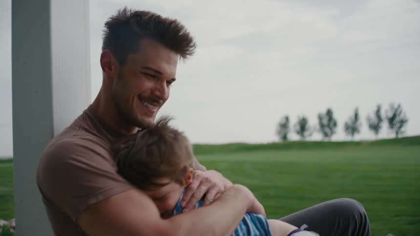 Father and young son sitting outdoors sharing a curious moment together