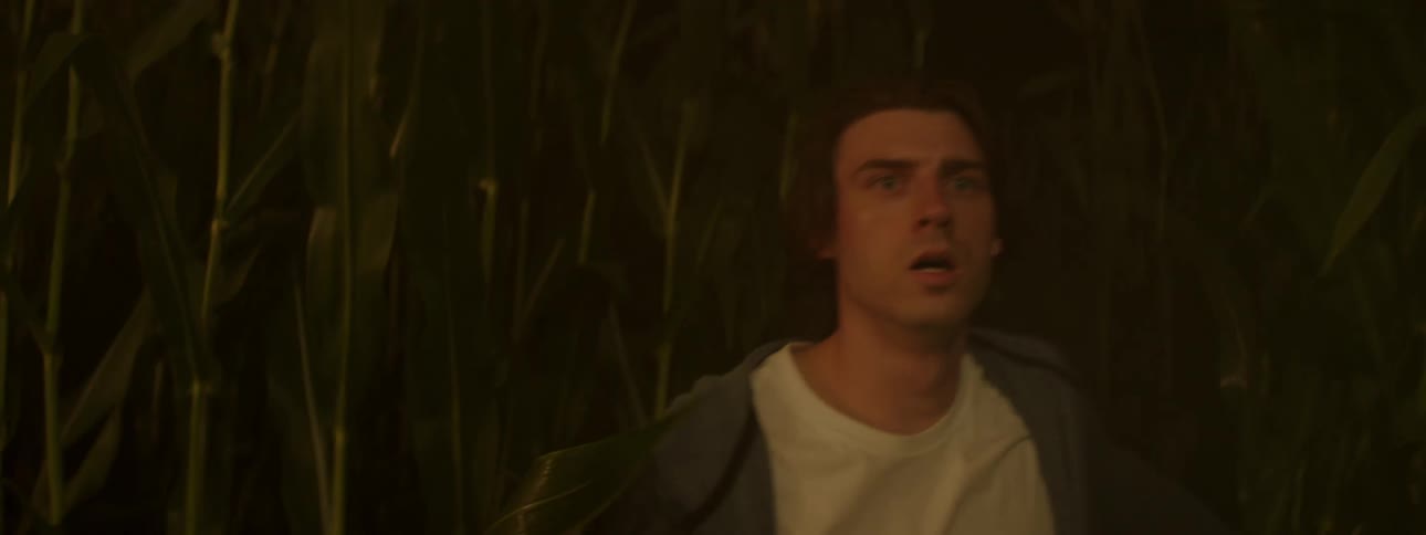 Man running in a cornfield with a flashlight in his hand