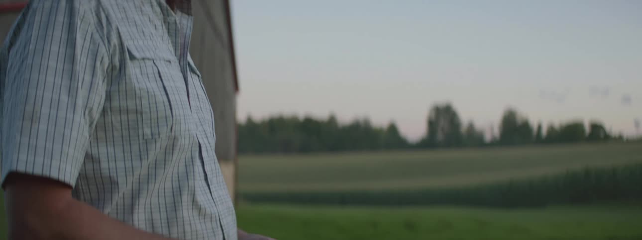 A man is standing outdoors near a barn