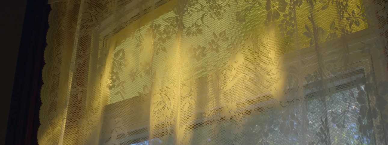 A window curtain moving with an incoming breeze