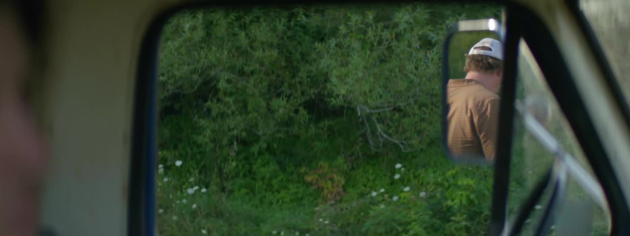 A man looking at his reflection in the trucks side mirror and walking away