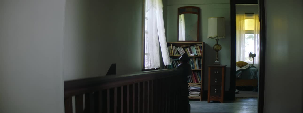 A curtain sways in the wind in the corridor of a house during the day