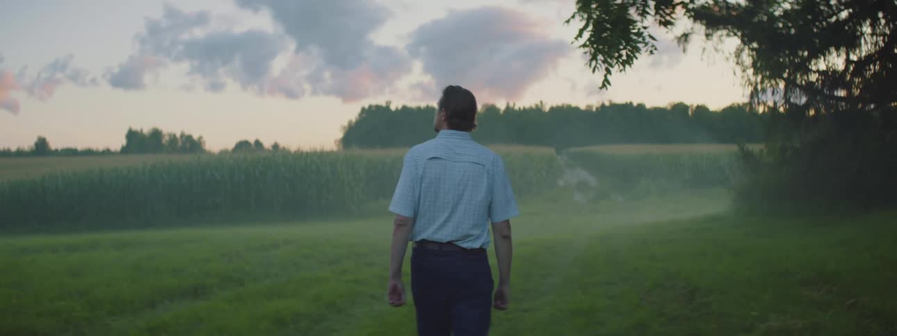 Man walking and contemplating as he looks around his corn field