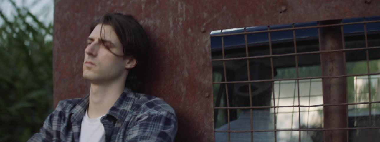 A sad young man rides in the back of a pickup truck