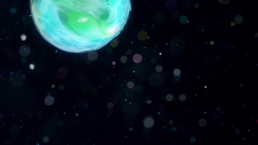 A blue and green globe moves across the darkness among small spheres and glowing orbs of light