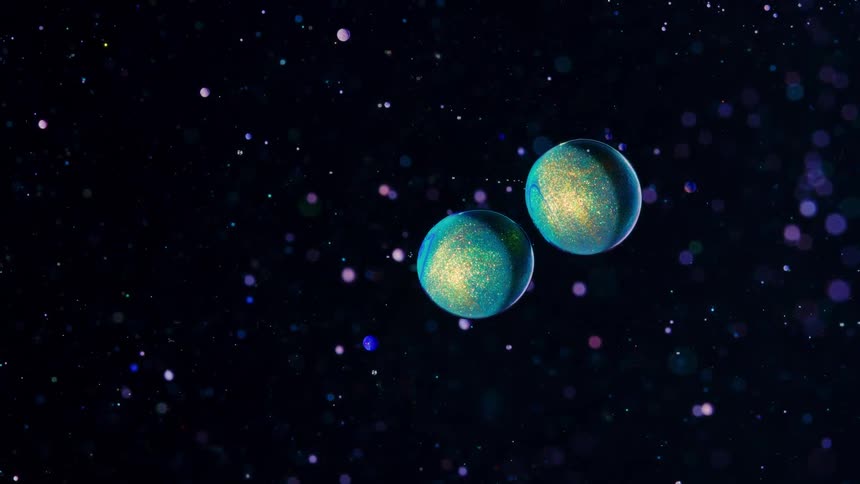 Two planets in blue and gold slowly flying through the universe