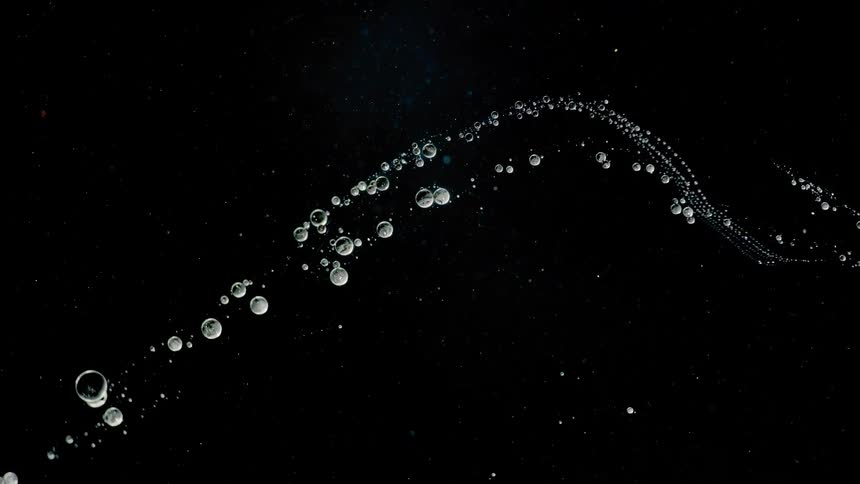 Many globes in line on a wavy path float in the darkness with stars in the distance