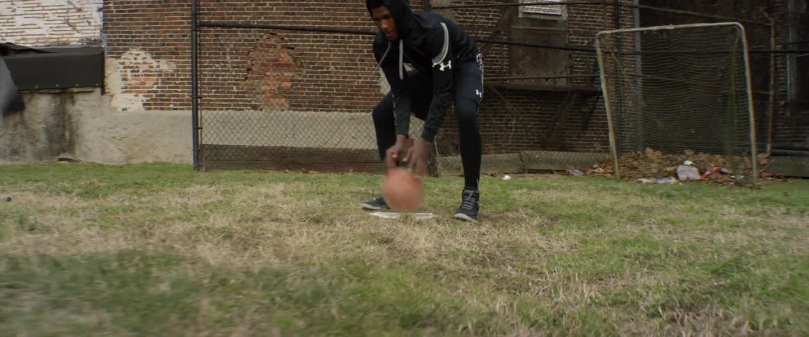 A man is dribbling a basketball on grass