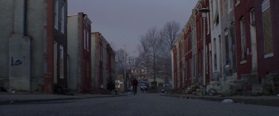 A man rides his bicycle down a street lined with homes