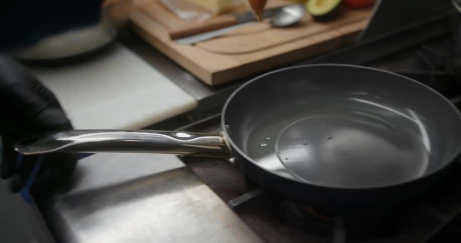 Close up of a person preparing chicken in a bowl and then placing it in a hot pan to cook