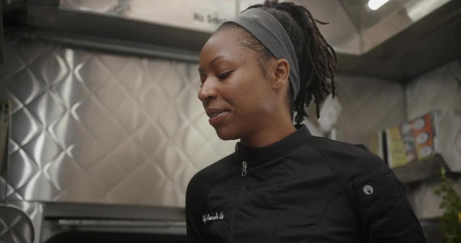 A woman smiles in a restaurant kitchen