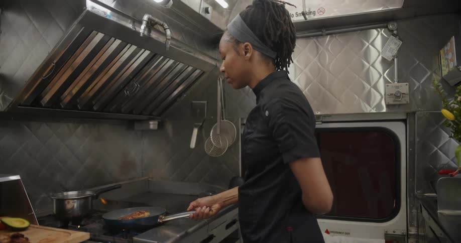 Woman chef cooking meat in a frying pan on the stove in the kitchen