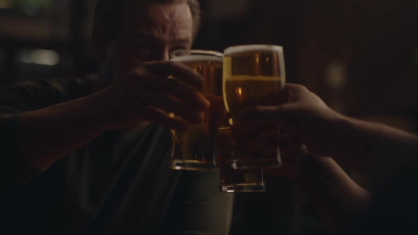 Glasses with beer in them beer pushed together by three friends as they cheers