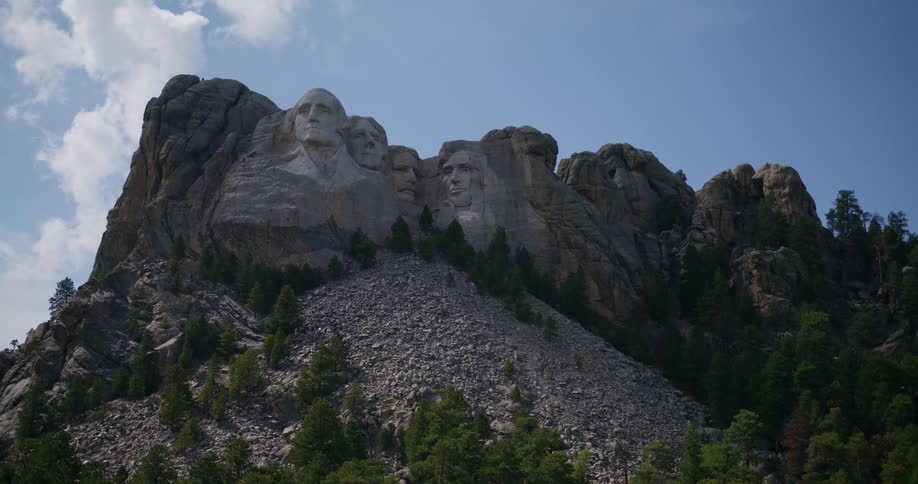 Camera pans down from a cloudy sky to reveal a shot of mount rushmore