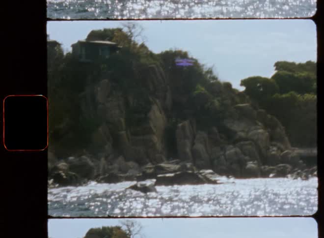 People stand at rail overlooking ocean a short distance from houses sitting on top of seaside cliffs