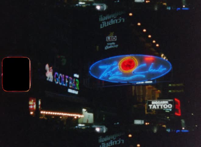 A city street lit up with neon store signs at night as people walk around