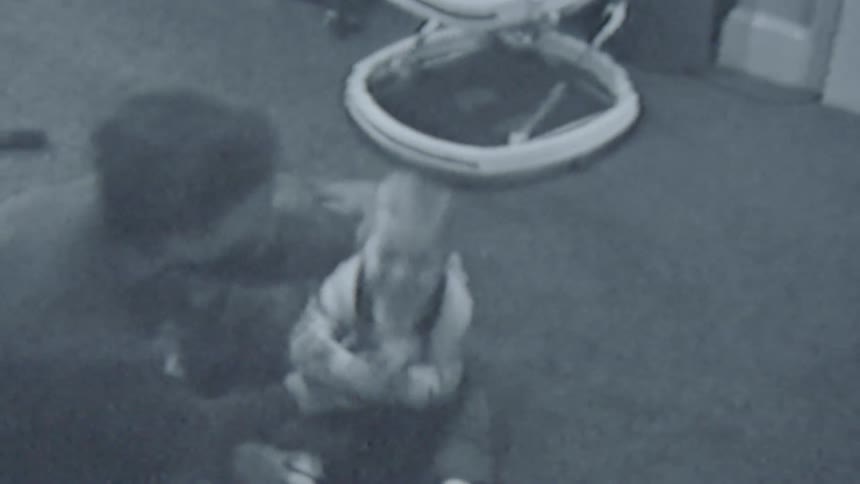 A mother tries teaching her toddler son to walk by holding him but he falls lightly on his bum