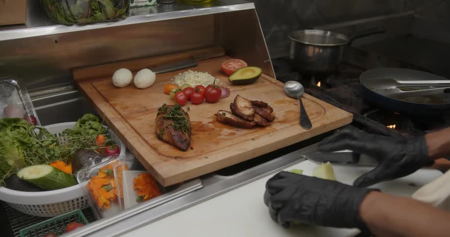 A restaurant chef cuts on lettuce while preparing a food board