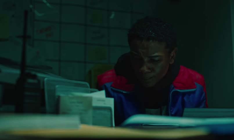 A teenage boy sitting at a desk looking downa nd sad