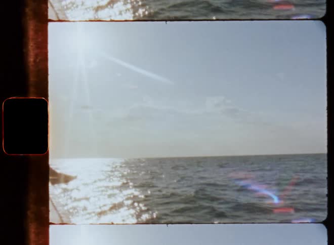Open ocean waters with waves crashing over the surface and a boats railing as it sails the ocean
