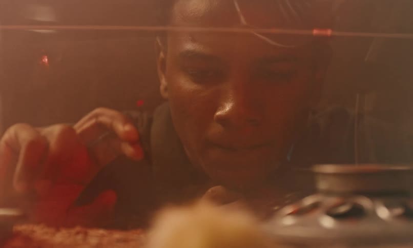 A teenage boy walking into a classroom towards a chick in a tank the boy kneeling in front of it and looking sad