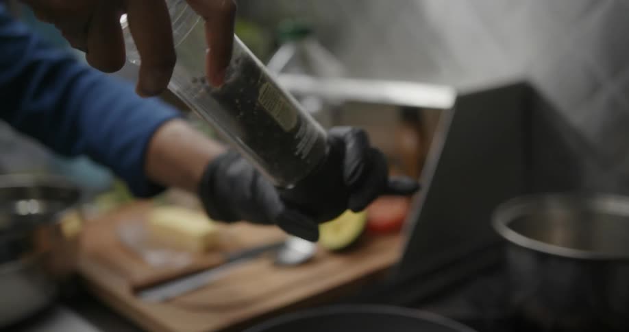 A close up of a person grinding pepper over food they are preparing