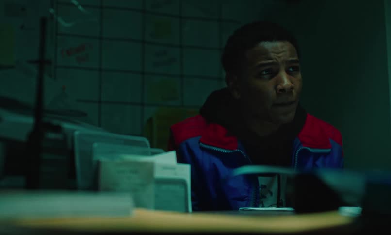 Teenage boy sitting in an office leaning forward looking concerned and looking down