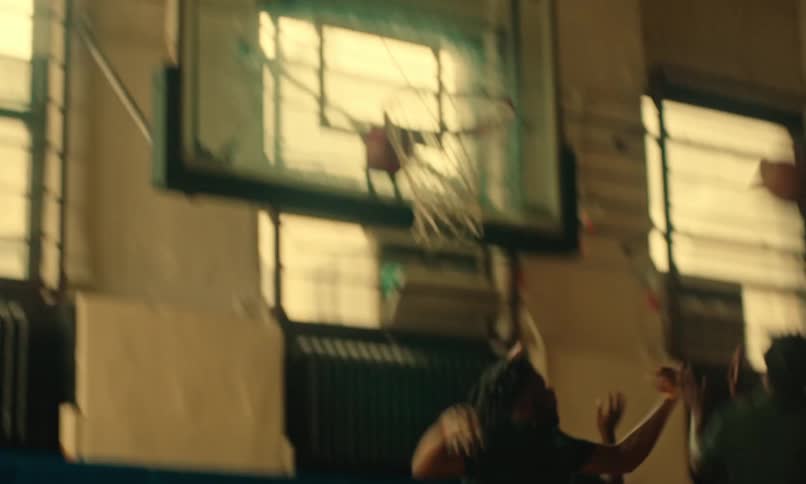 Group of men playing basketball on a gymnasium court indoors as they run up and down the court shooting the ball