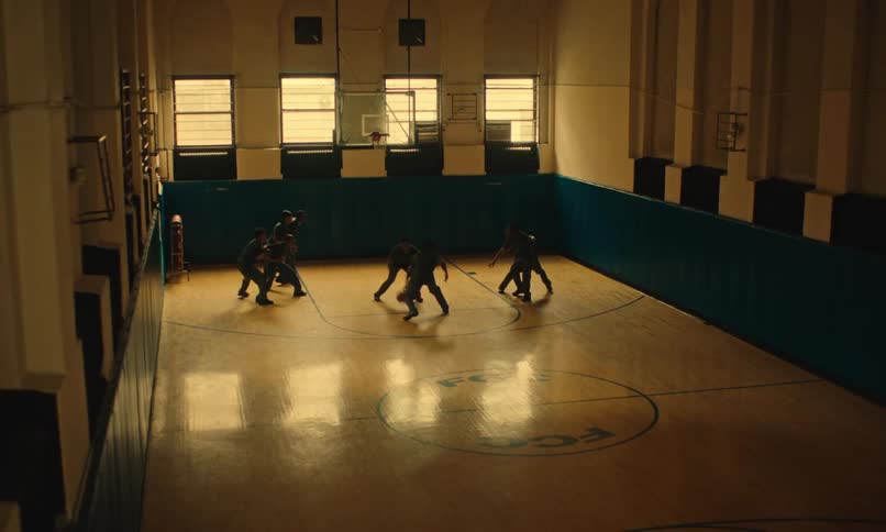A group of male students playing basketball in a gymnasium during the day