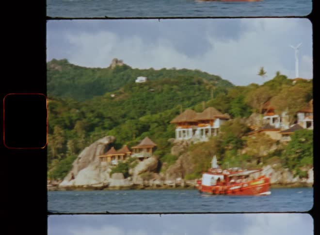 Houses on a coastline built into trees as boats sit in the water sailing on the coast