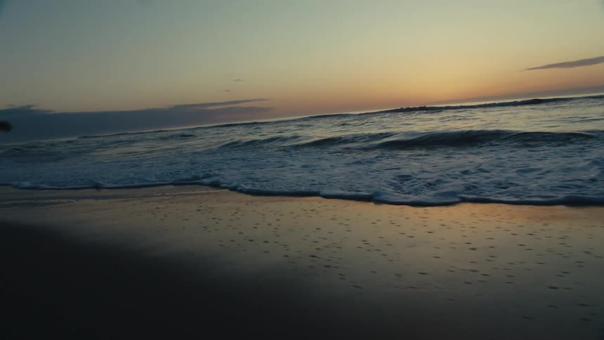 Child running on the beach near the sea during sunset