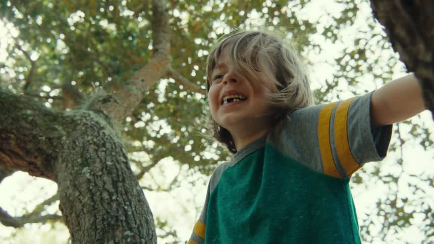 Blonde girl sitting in tree with missing teeth laughs