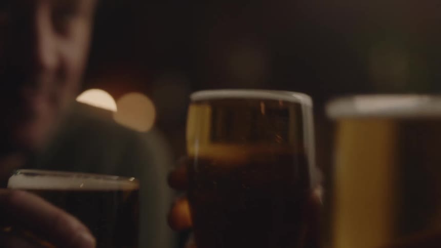 Three glasses with alcohol in them being pushed together by three friends cheering